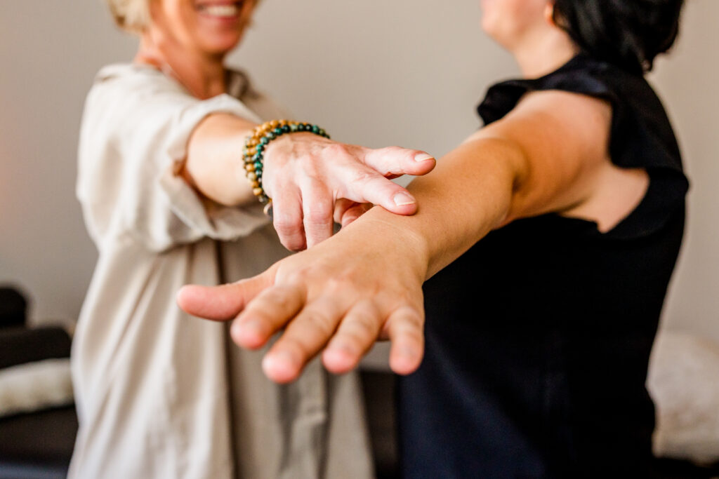 Nahaufnahme: kinesiologischer Muskeltest am ausgestreckten Arm in ruhiger Praxis – sanfte Berührung zur energetischen Balance.
